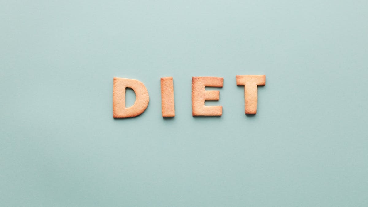 Alphabet cookies spelling 'diet' on a soft turquoise background, shot as a flat lay.